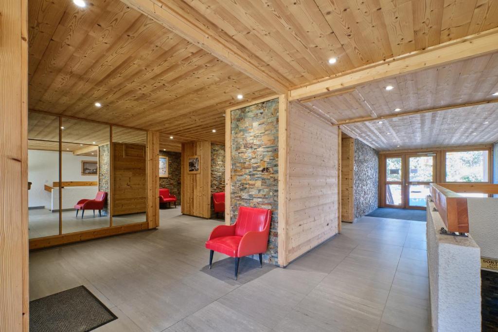 Cette chambre est dotée de chaises rouges et d'un mur en pierre. dans l'établissement La montagne, à Les Deux Alpes