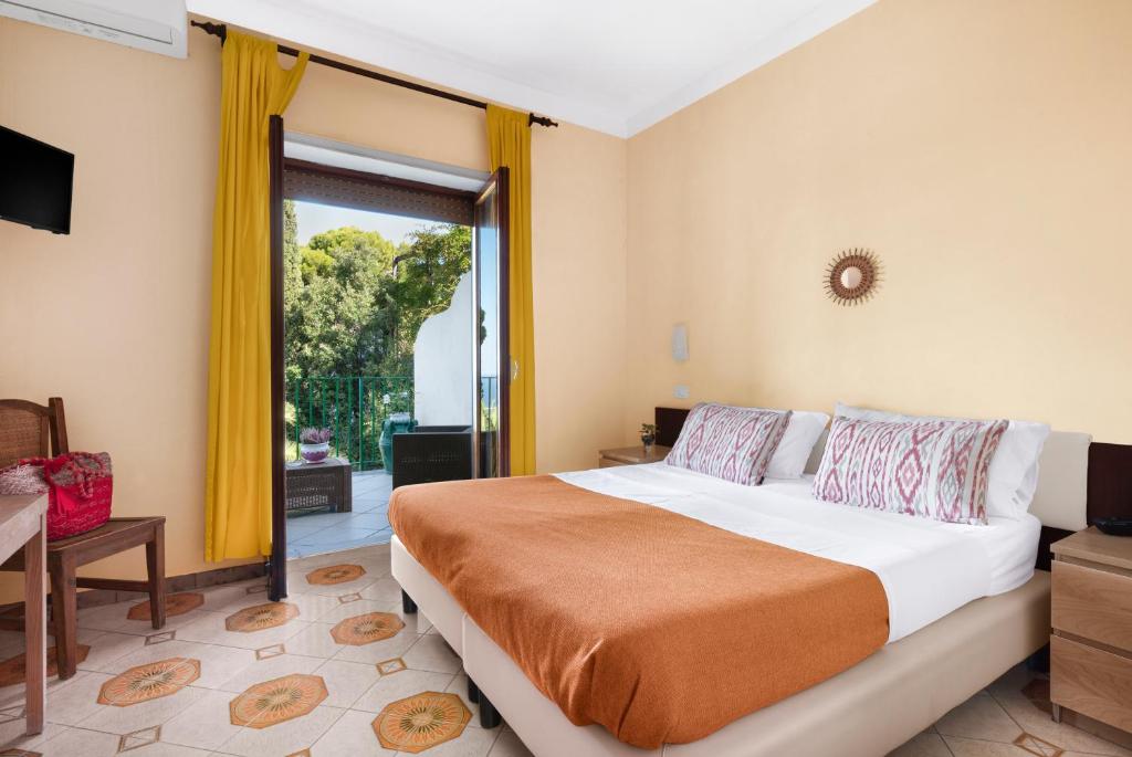une chambre avec un grand lit et une grande fenêtre dans l'établissement Hotel Desiree, à Sorrente