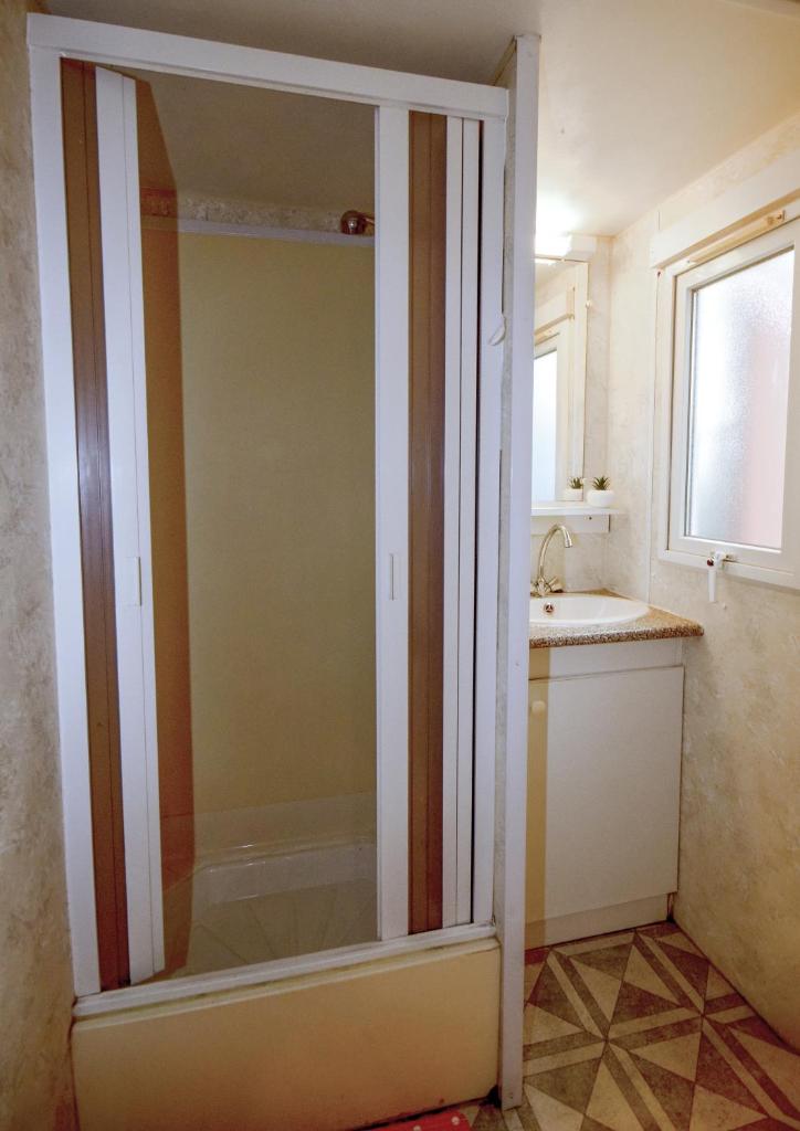 La salle de bains est pourvue d'une porte de douche et d'un lavabo. dans l'établissement Mobil-home climatisé, camping 3étoiles, 5 min du Lac et à 15 min de Mimizan-Plage, à Sainte-Eulalie-en-Born