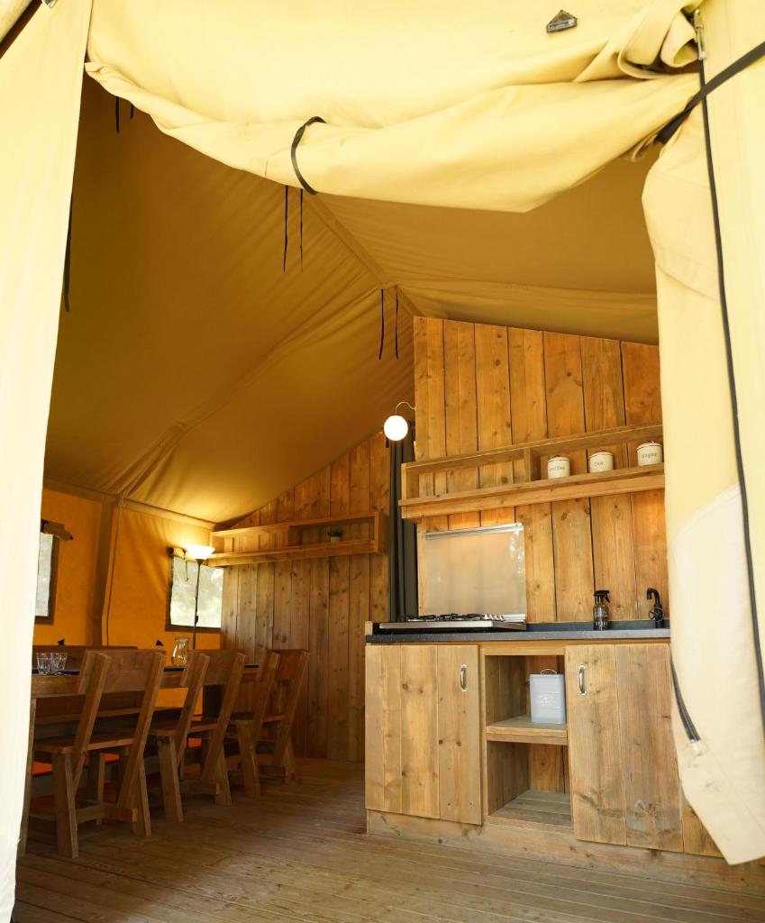 une tente avec des chaises et une cuisine. dans l'établissement Tente Safari Eco Lodge 6 Personnes, à Castillon-Debats 18 autres photos
