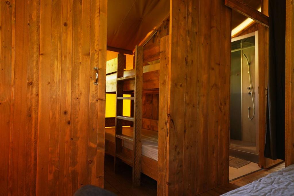 Cette chambre en bois comprend un lit et une douche. dans l'établissement Tente Safari Eco Lodge 6 Personnes, à Castillon-Debats