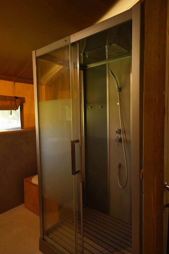 une douche avec une porte vitrée dans une salle de bain dans l'établissement Tente Safari Eco Lodge 6 Personnes, à Castillon-Debats