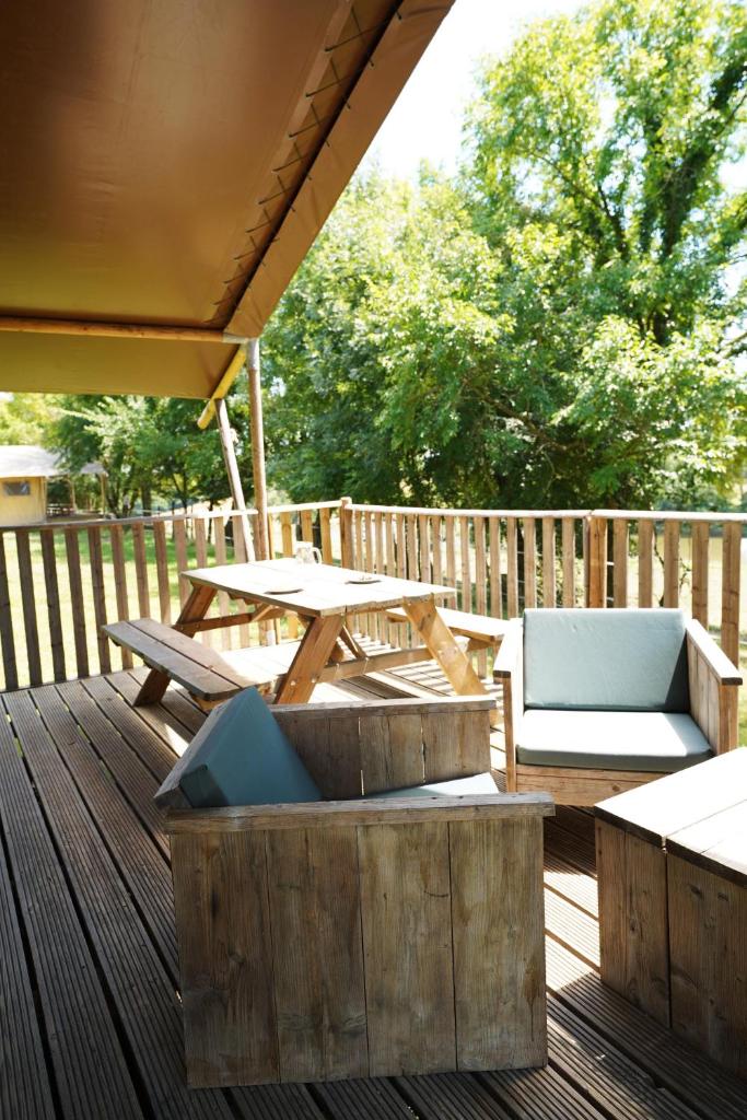 une terrasse en bois avec une table de pique-nique et des chaises dans l'établissement Tente Safari Eco Lodge 6 Personnes, à Castillon-Debats