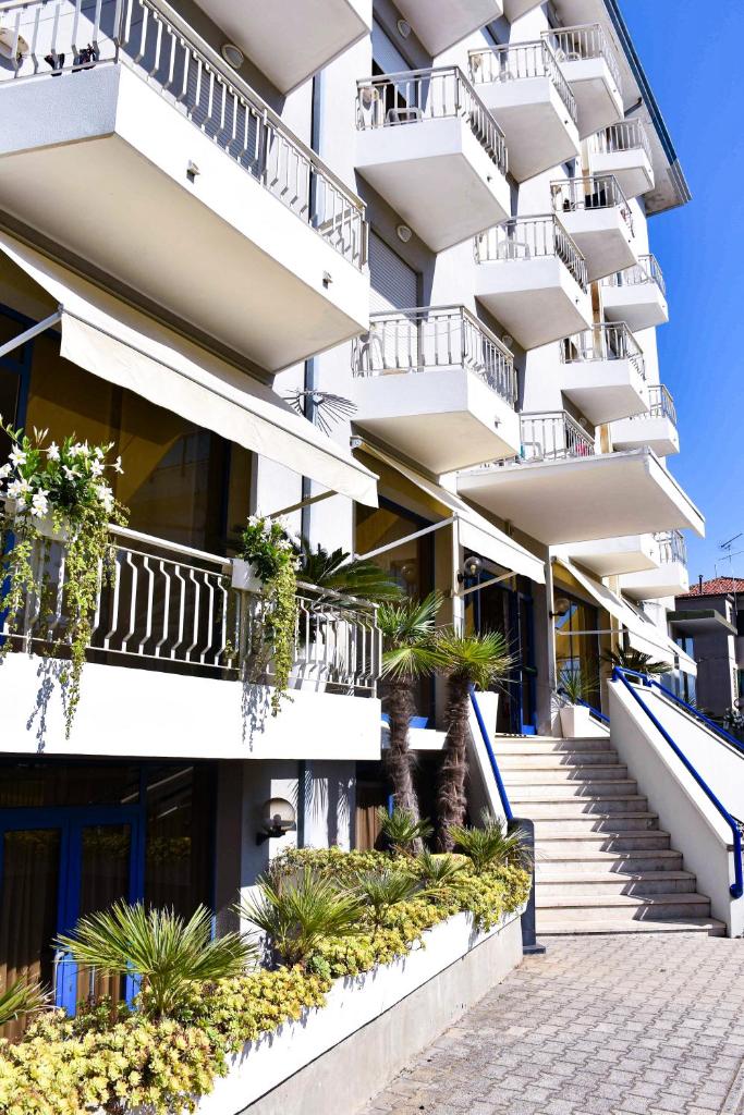 un immeuble d'appartements avec des balcons blancs et des plantes dans l'établissement Hotel Umberto, à Lido di Jesolo
