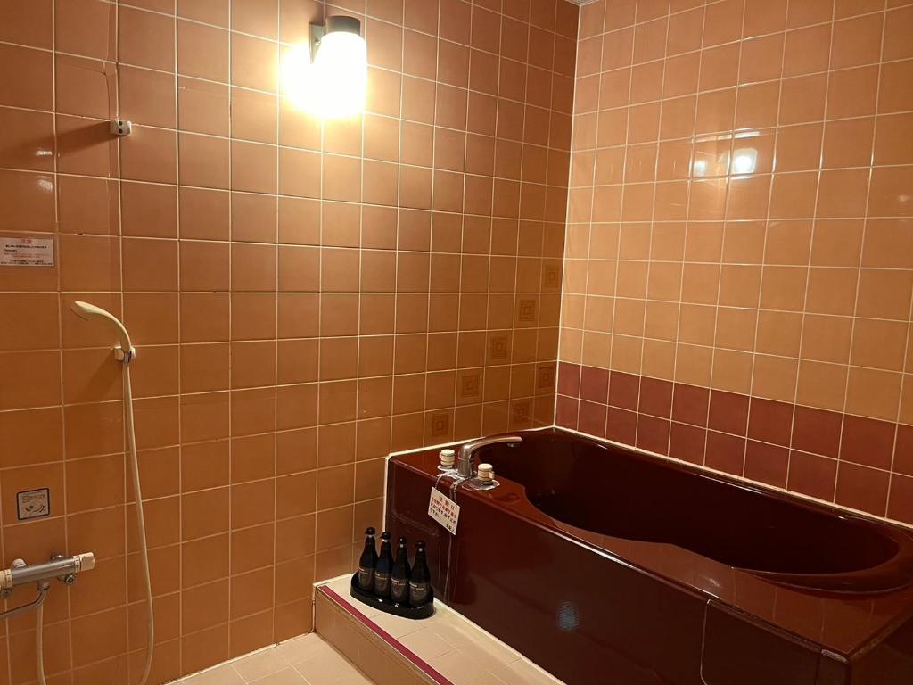 La salle de bains est pourvue d'une baignoire et d'une lumière sur le mur. dans l'établissement adult only ホテルシャルム, à Itoigawa