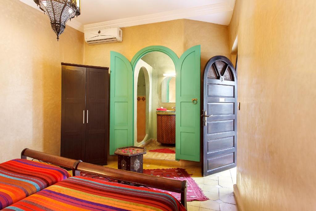 Cette chambre dispose de portes vertes et d'un lit. dans l'établissement Riad La Kahana, à Marrakech 29 autres photos