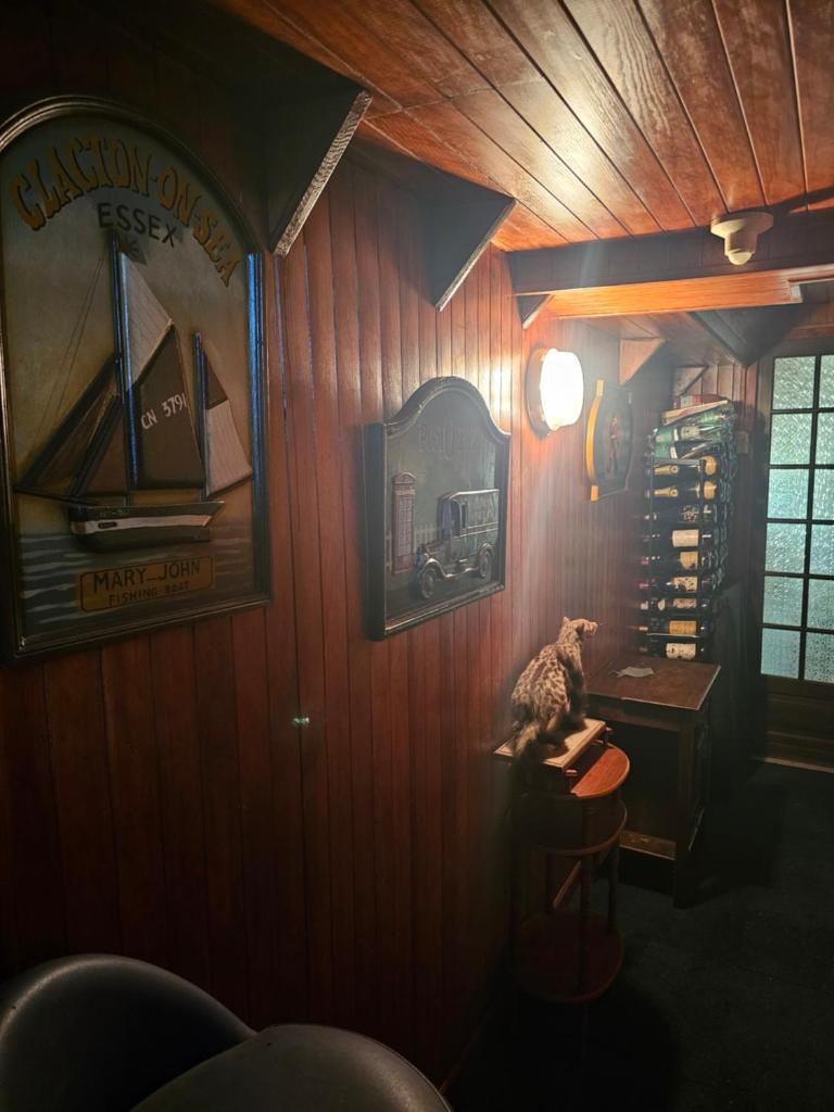 un chat assis sur un tabouret dans une pièce aux murs en bois dans l'établissement St Christopher, à Creil
