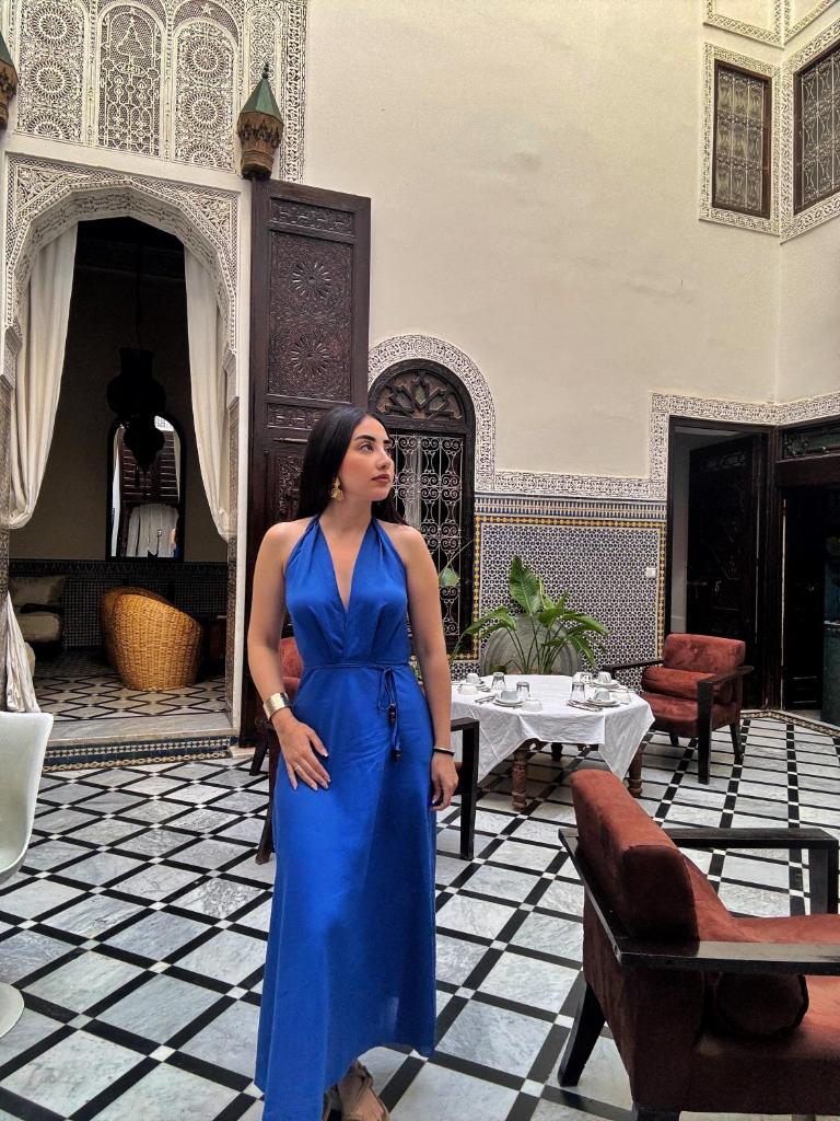 une femme en tenue bleue debout dans une pièce dans l'établissement Riad Tizwa Fes, à Fès
