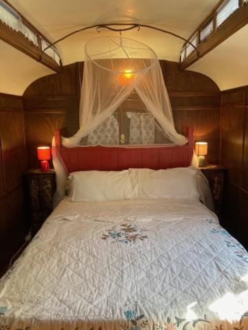 une chambre avec un grand lit à baldaquin dans l'établissement Idyllic Roulotte, à Les Assions