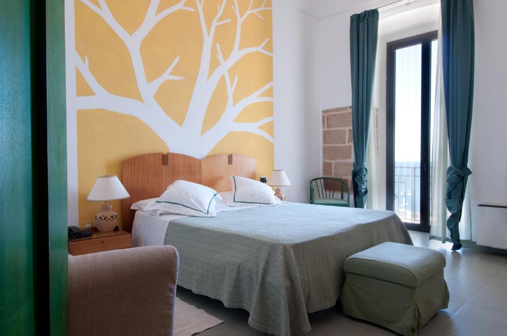 - une chambre avec un lit et un arbre sur le mur dans l'établissement Grand Hotel Mediterraneo, à Santa Cesarea Terme