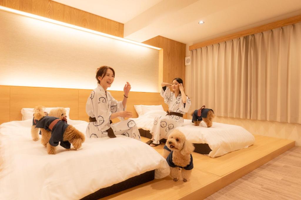 trois femmes en kimono avec leurs chiens sur des lits dans l'établissement Komatsuya Hachinobou, à Izunokuni