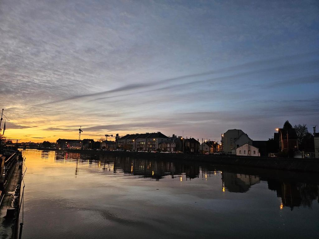 - une vue sur une rivière au coucher du soleil avec une ville dans l'établissement peniche logement, à Creil