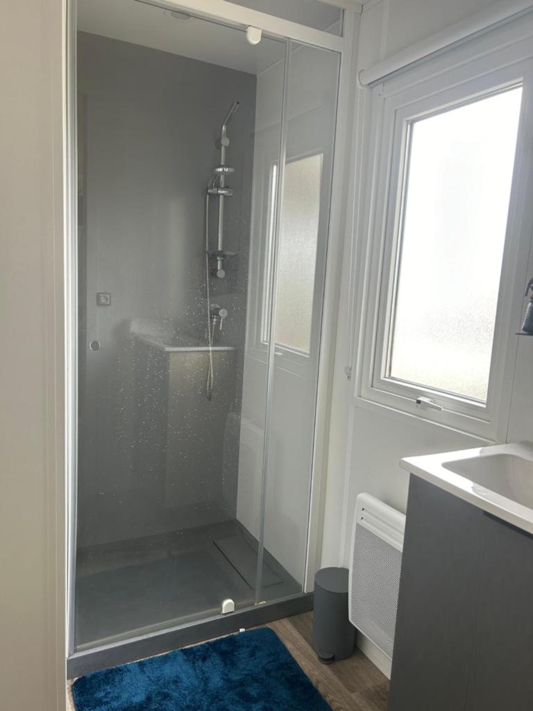 une douche avec une porte vitrée dans une salle de bain dans l'établissement Camping Les Viviers chez So Claouey, à Lège-Cap-Ferret