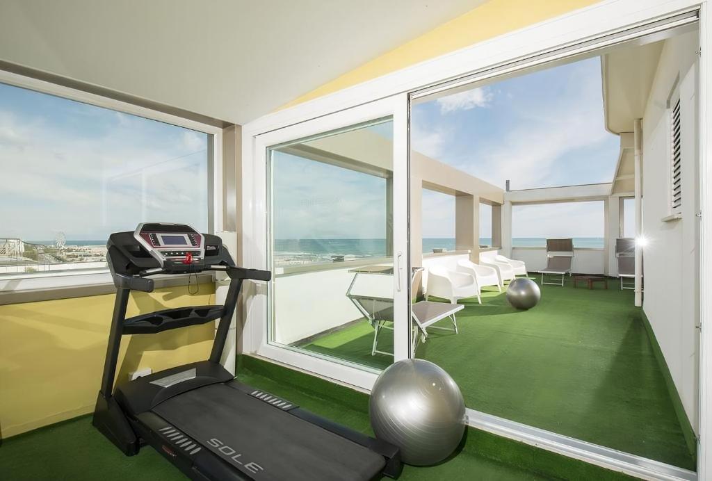 - une salle de sport avec un tapis de course et une grande fenêtre dans l'établissement Villa dei Gelsomini & National Hotel dal 1903, à Rimini