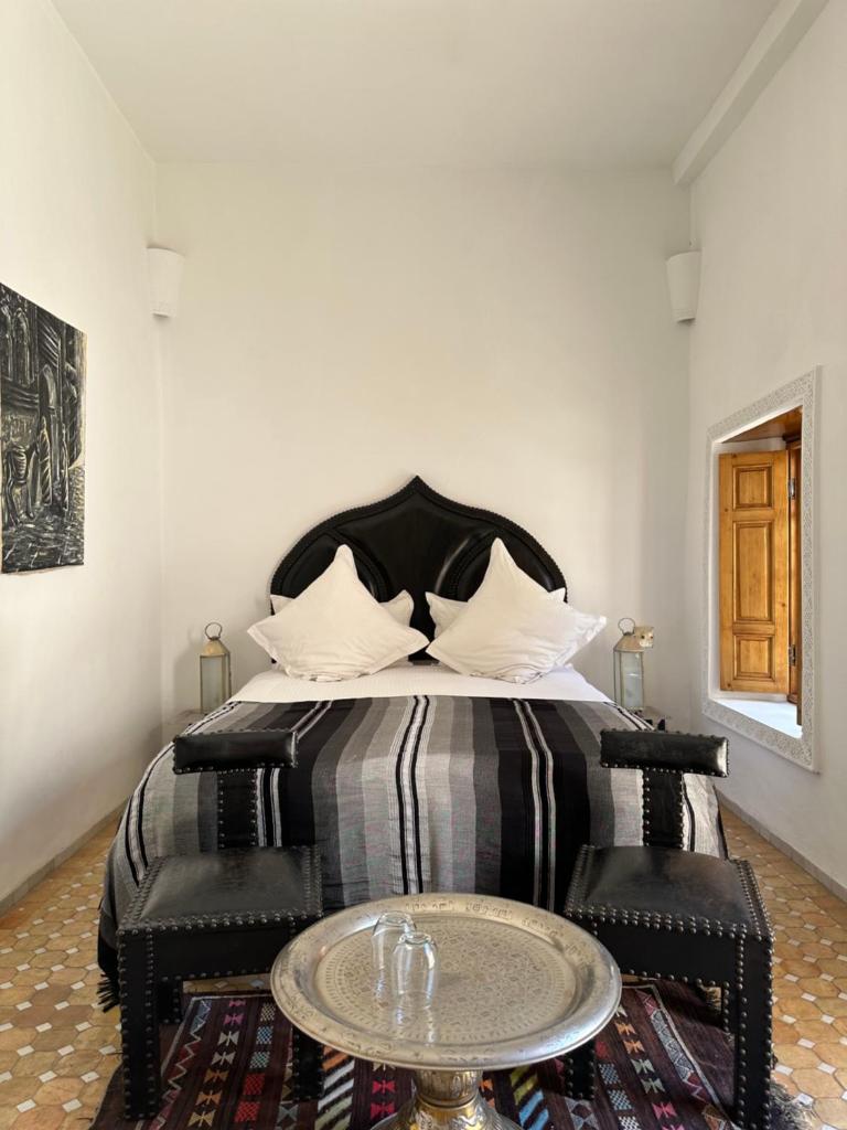 une chambre avec un lit avec deux chaises et une table dans l'établissement Dar Faracha Fes, à Fès