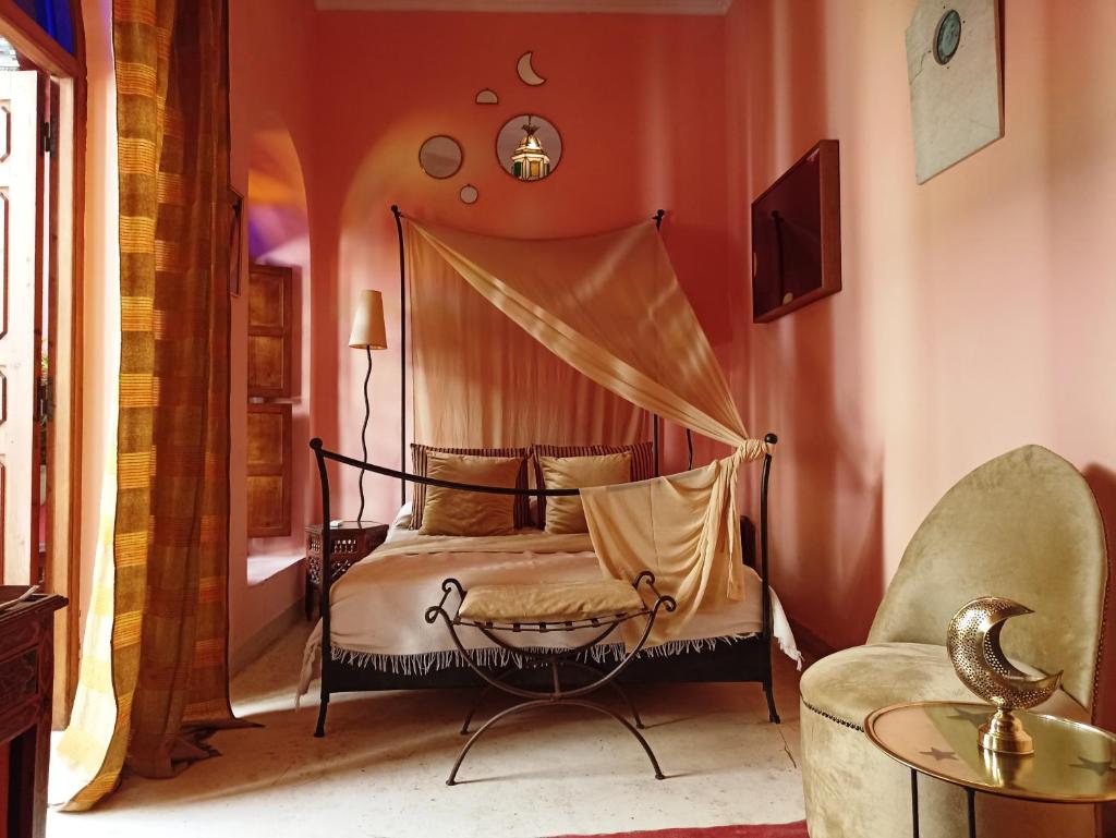 une chambre avec un lit à baldaquin et une chaise dans l'établissement Dar Taliwint, à Marrakech