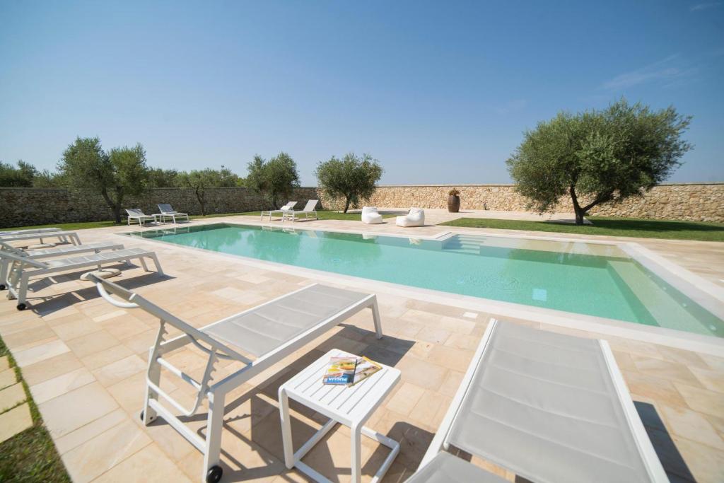 une piscine avec des chaises et une table dans l'établissement Lisària Villa Delle Meraviglie With Pool, à Castrignano deʼ Greci