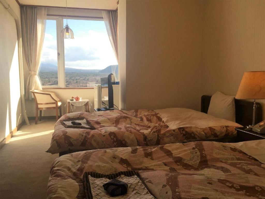- 2 lits dans une chambre d'hôtel avec une grande fenêtre dans l'établissement Shoji Lake Hotel, à Fujikawaguchiko