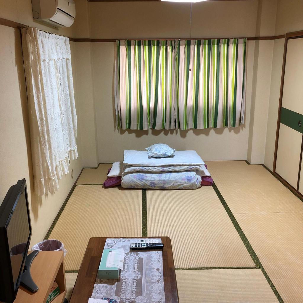 une chambre avec un lit, une table et une fenêtre dans l'établissement Imazato Ryokan, à Osaka