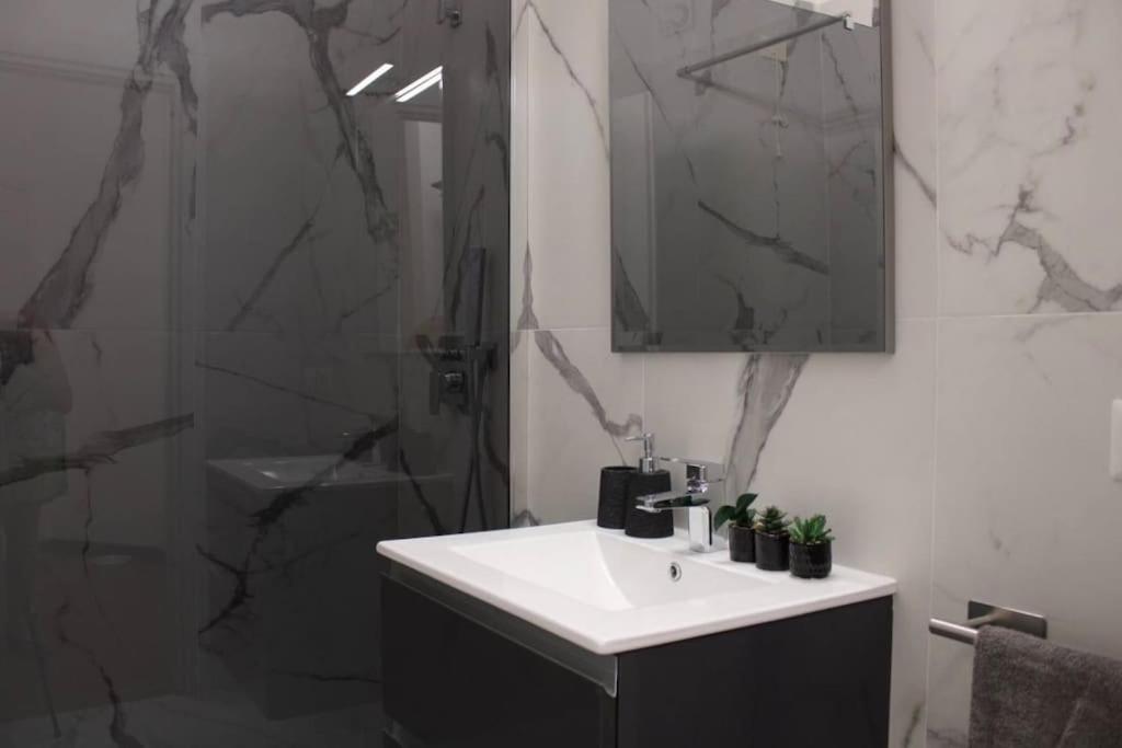 une salle de bain avec un lavabo et une douche avec un miroir dans l'établissement Villa Nina - Lussuosa Villa con piscina privata a Stintino, à Cuile Pazzoni