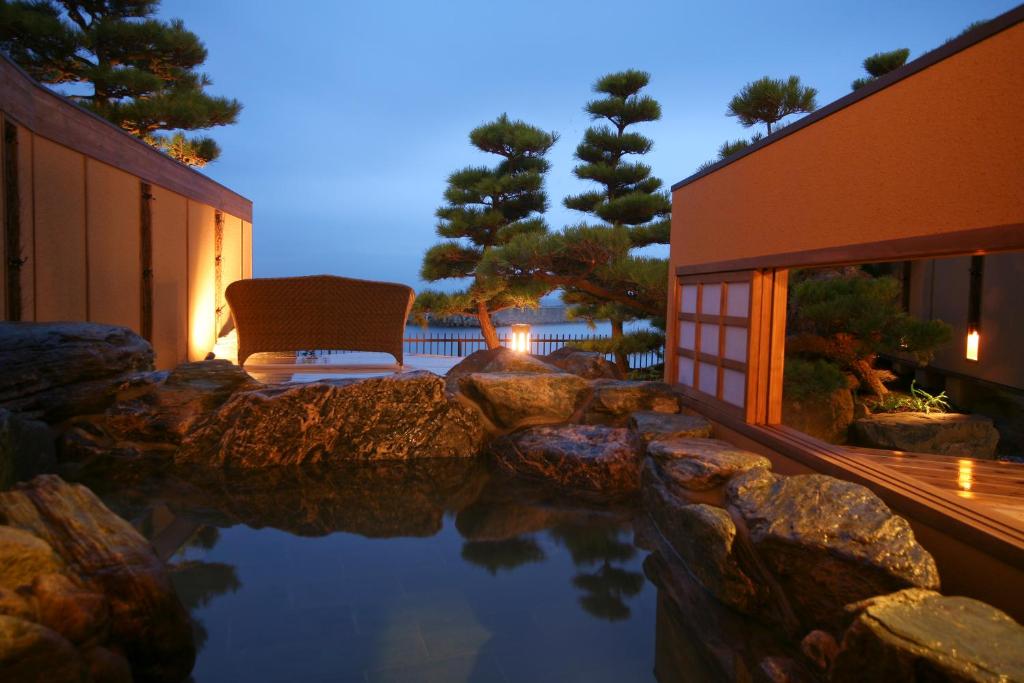 une piscine d'eau avec une chaise et un bâtiment dans l'établissement Hotel New Awaji, à Sumoto
