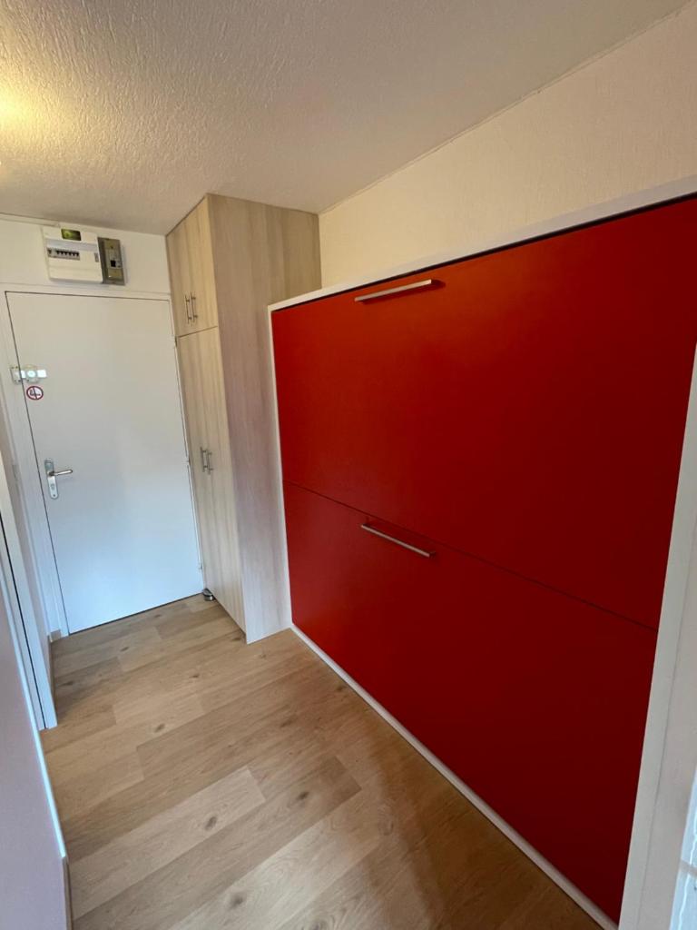 une armoire rouge dans une pièce avec porte dans l'établissement Studio rénové 2 adultes 2 enfants - Tignes Lavachet - Vue Montagne plein sud, à Tignes