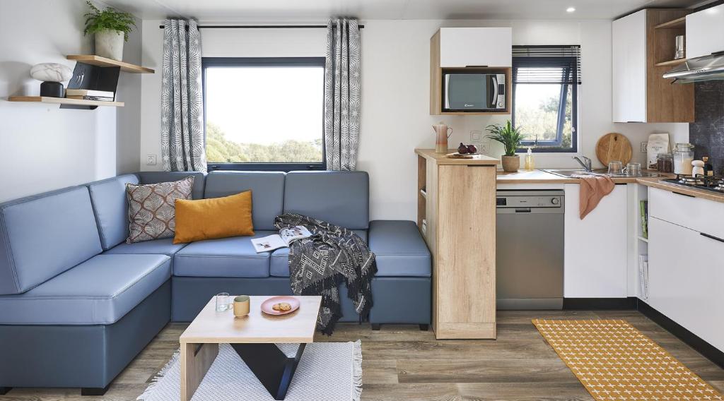 un salon avec un canapé bleu et une cuisine dans l'établissement Camping Paradis Le Grand' R, à La Faute-sur-Mer
