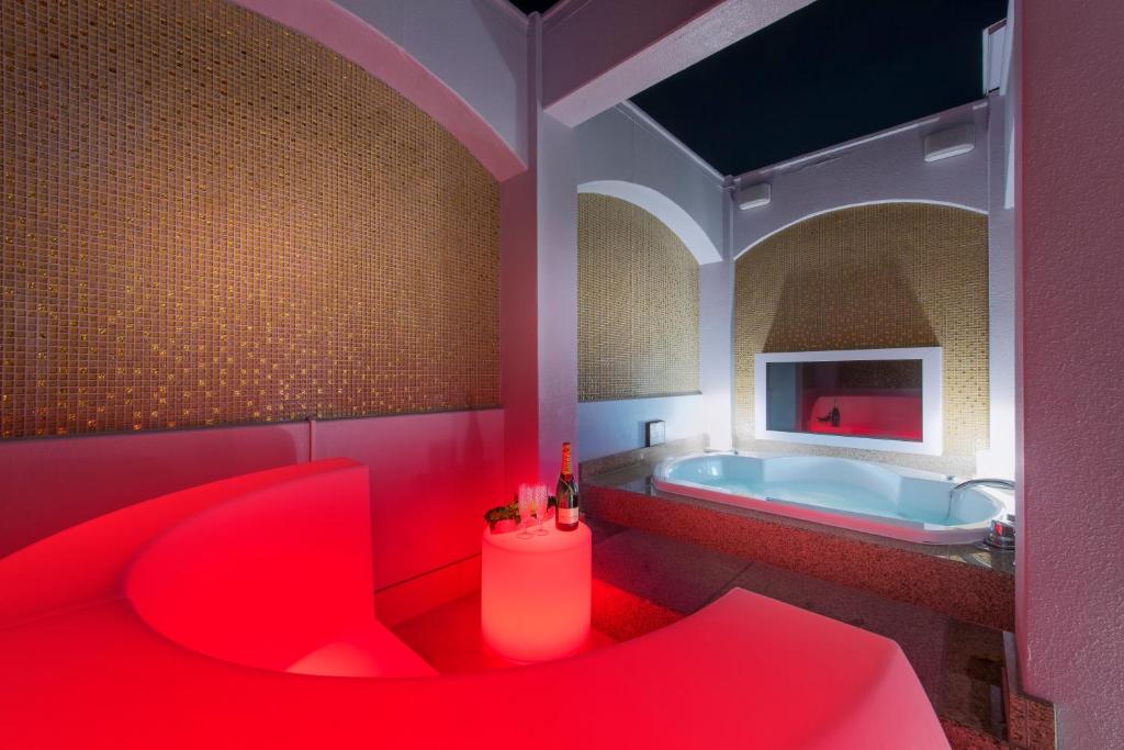La salle de bains rouge est pourvue d'une baignoire et d'un fauteuil rouge. dans l'établissement ホテルディオールセブン郡山, à Koriyama