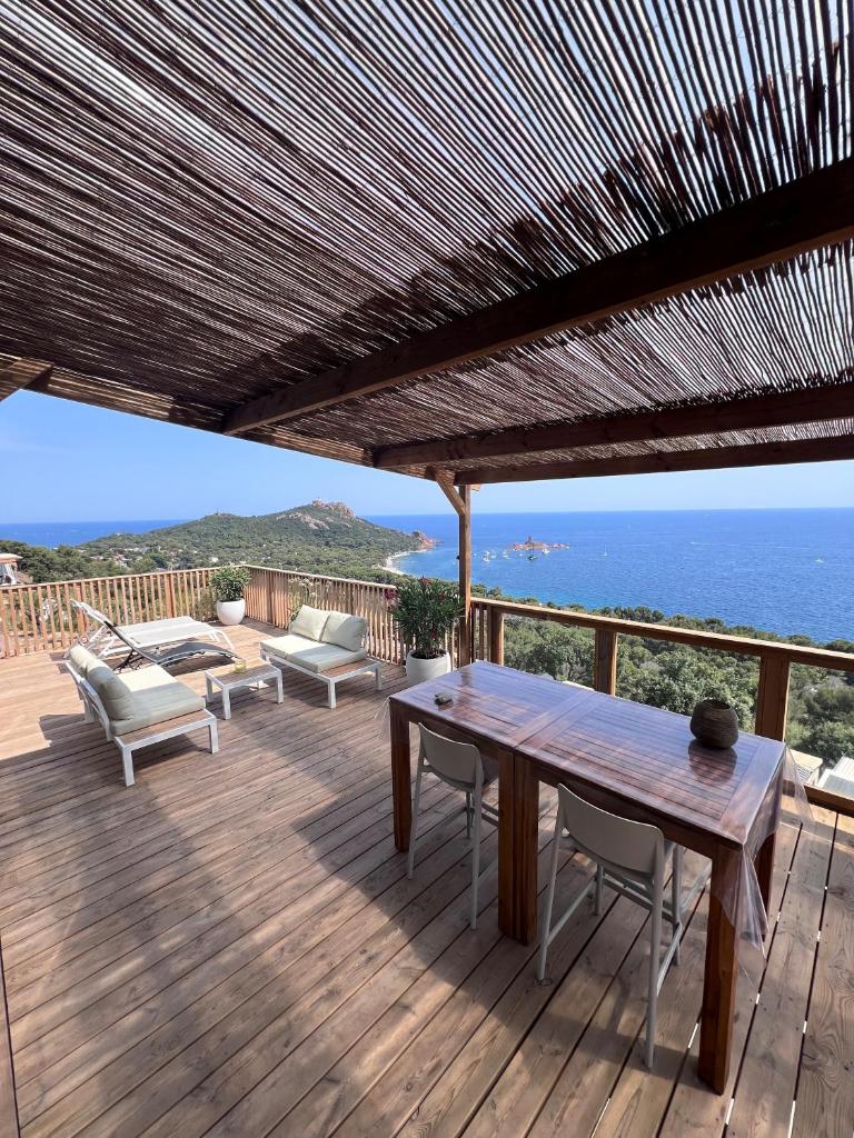 une terrasse en bois avec une table et des chaises et l'océan dans l'établissement Mobile Evasion okpl SEGUR, à Saint-Raphaël