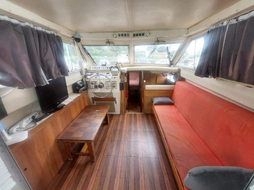 une vue de l'intérieur d'un bateau avec un banc et une télévision dans l'établissement Escapade en Bateau VINTAGE terrasse mini spa option payante, à Seurre