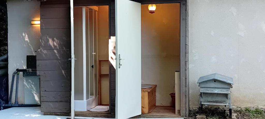 une porte ouverte menant à une chambre avec une poubelle dans l'établissement Yourte en pleine nature, à Dampierre