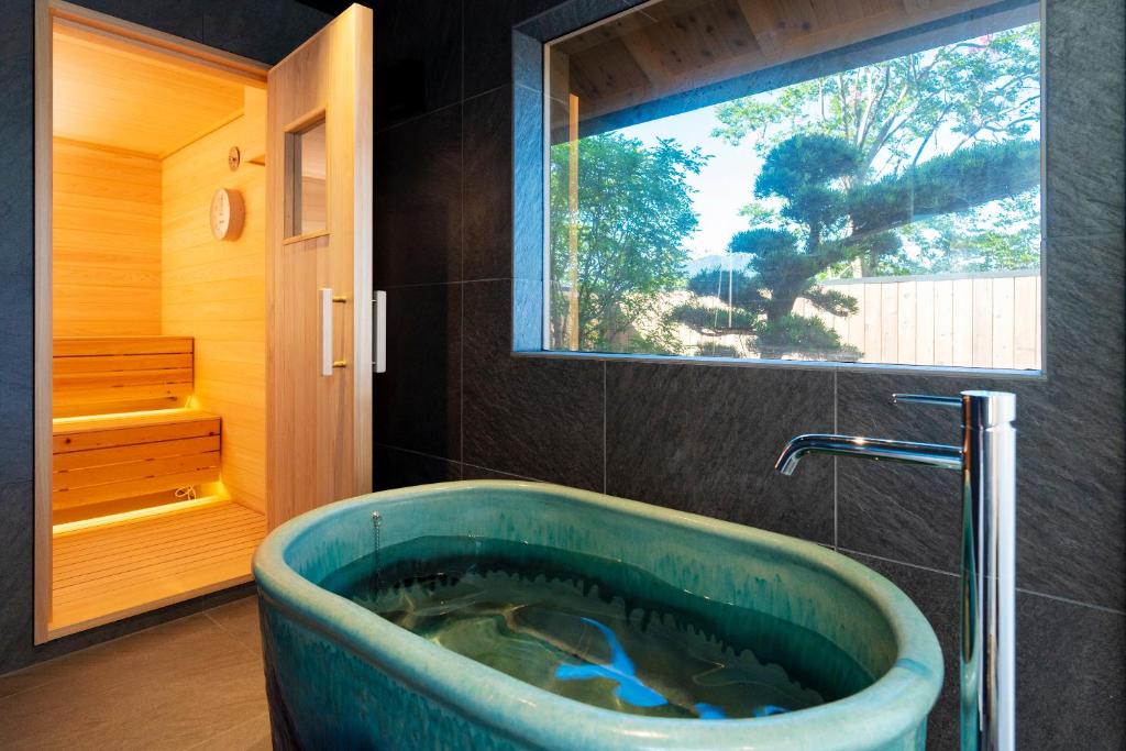 La salle de bains est pourvue d'une grande baignoire et d'une fenêtre. dans l'établissement Hotel Kitanoya, à Miyazu
