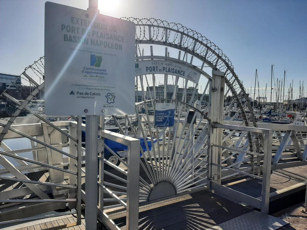 une roue ferris avec un signe devant elle dans l'établissement Le chant des mouettes - Voilier, à Boulogne-sur-Mer
