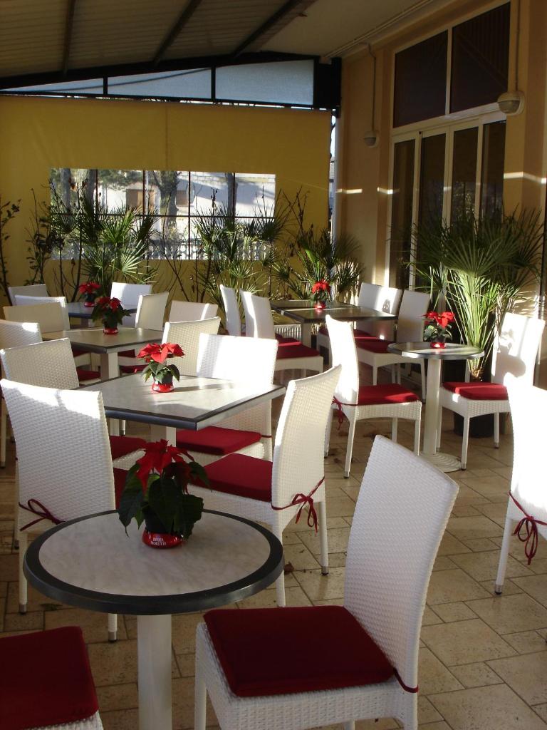un restaurant avec des tables blanches et des chaises blanches dans l'établissement Pensione Imperia, à Lignano Sabbiadoro