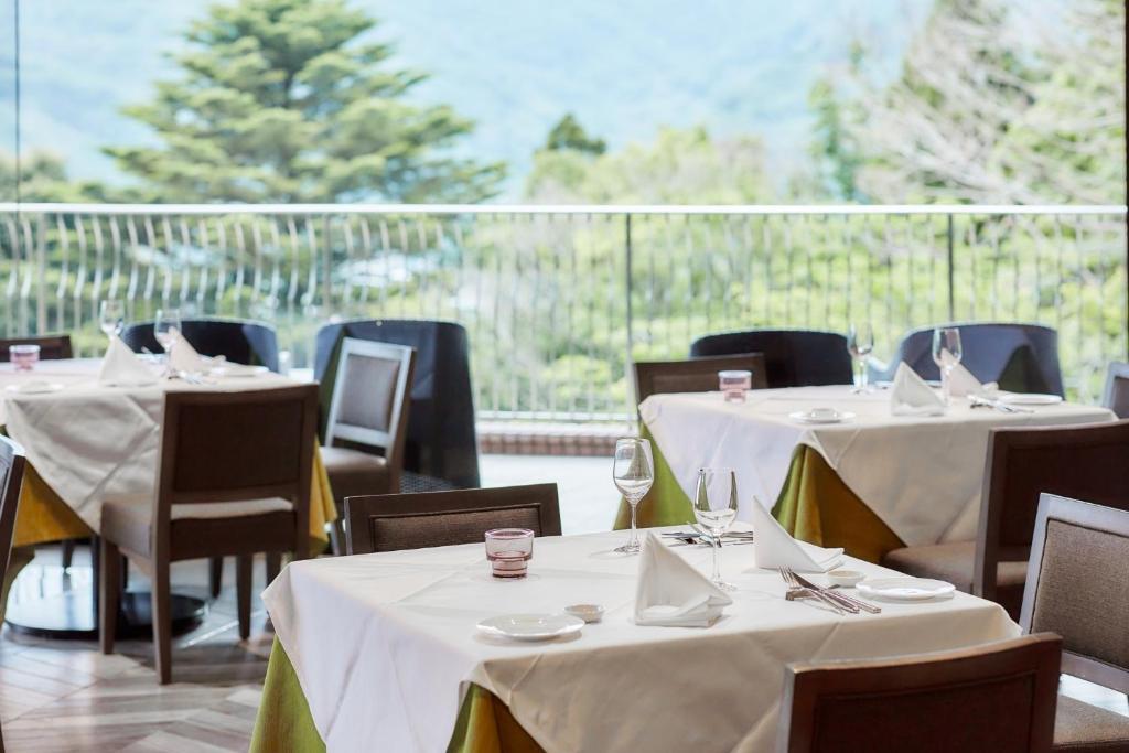 un restaurant avec des tables et des chaises blanches et un balcon dans l'établissement Hakone Elecasa Hotel and Spa, à Hakone 37 autres photos