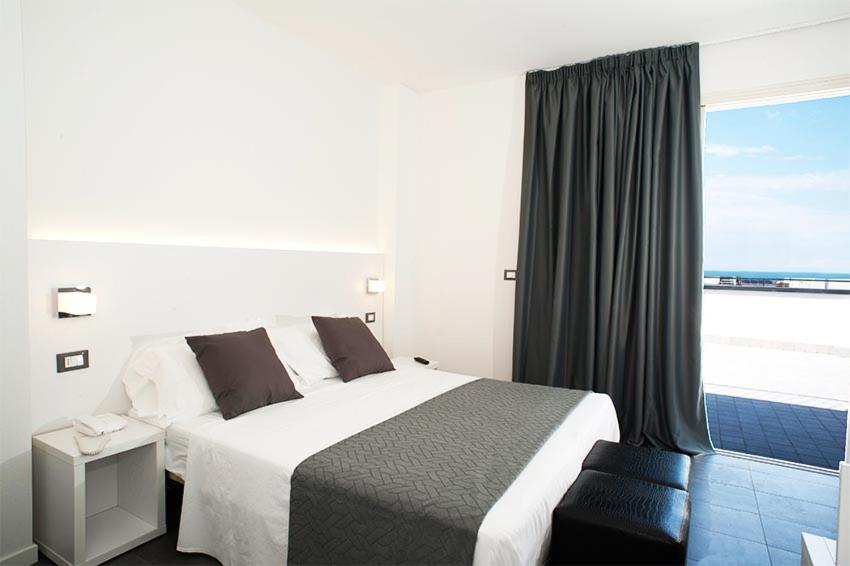 une chambre avec un lit et une fenêtre avec l'océan dans l'établissement Hotel Niagara, à Cattolica 28 autres photos