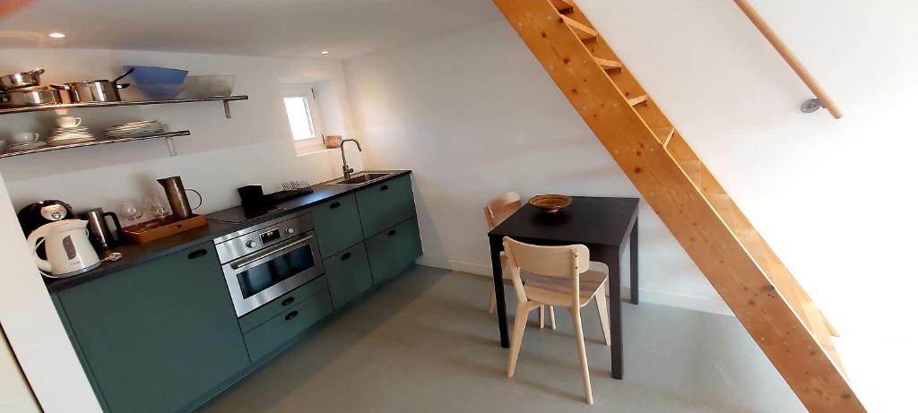 une petite cuisine avec des placards verts et une table dans l'établissement Gite Liberté, à Saint-Bonnet-Tronçais