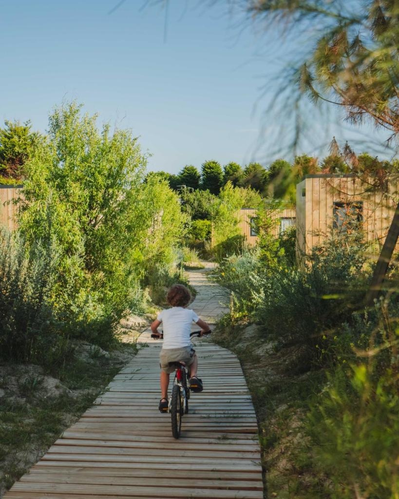 un jeune garçon faisant du vélo sur un sentier en bois dans l'établissement Sauvage, à Quiberon