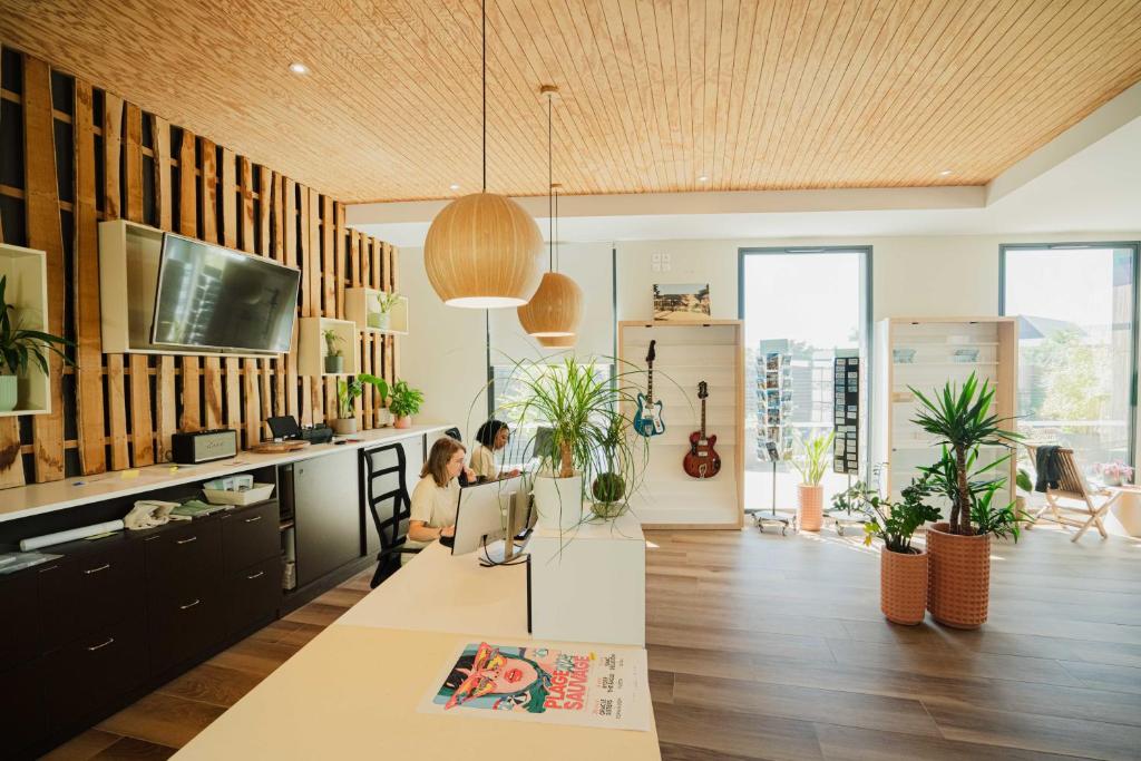 une femme assise à un bureau dans une pièce avec des plantes dans l'établissement Sauvage, à Quiberon