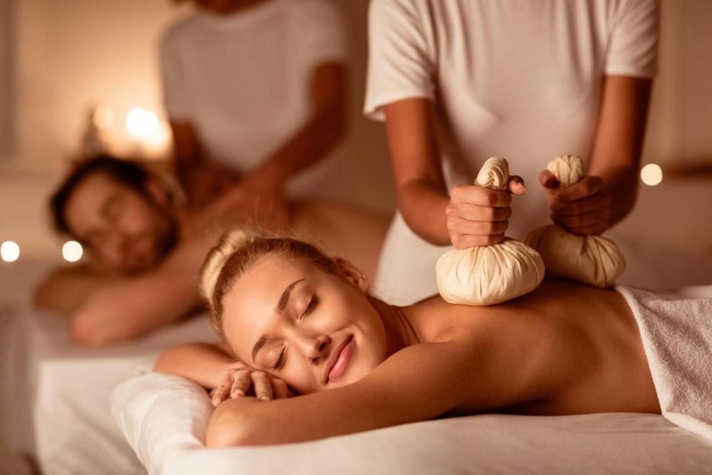 une femme allongée sur un lit recevant un massage dans l'établissement Happy Hotel Atelier Gardone Riviera Centro & Spa, à Gardone Riviera