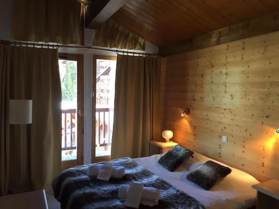 une chambre avec un grand lit avec un mur en bois dans l'établissement Duplex 170m2 avec terrasse vue domaine skiable ARCS2000, à Arc 1950