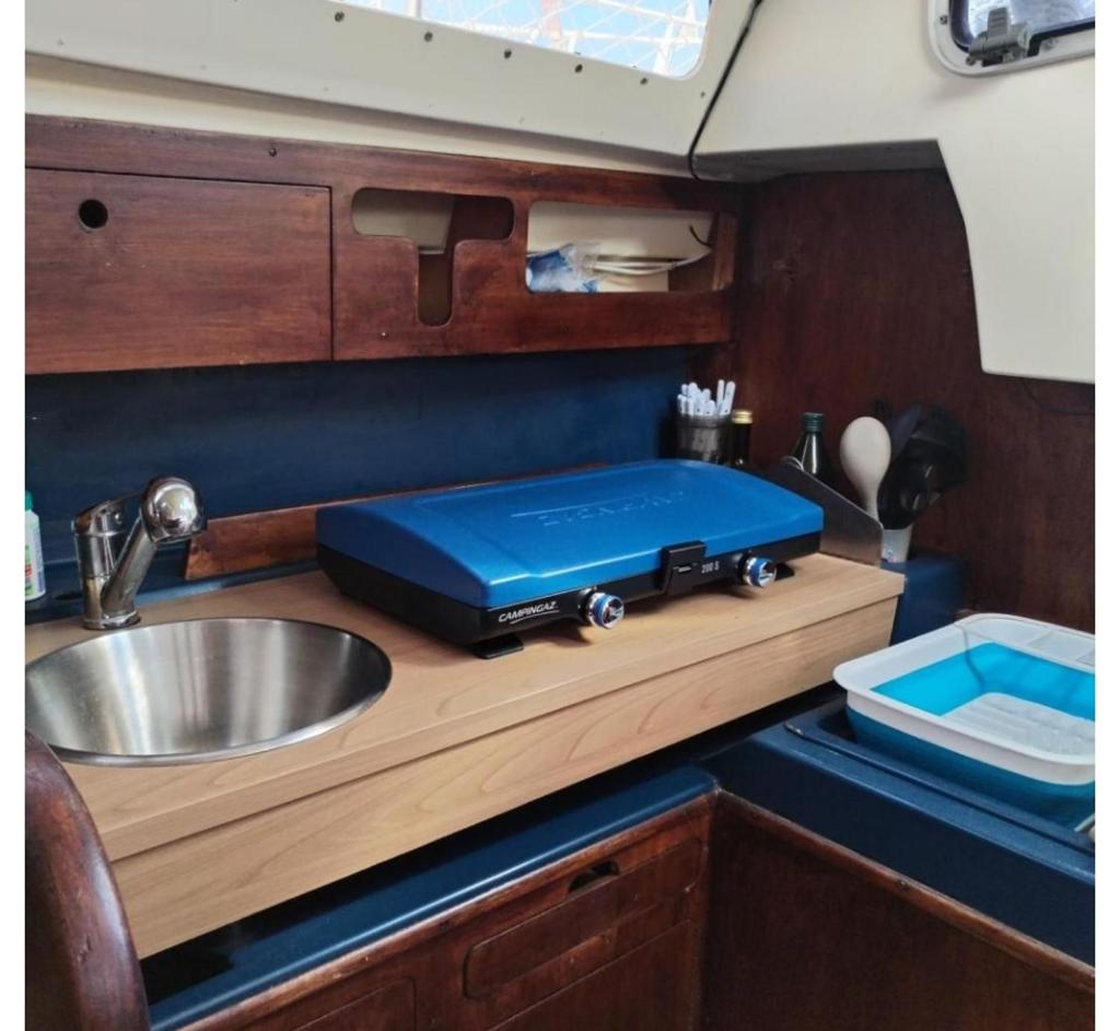 - un comptoir de cuisine avec une boîte bleue au-dessus d'un évier dans l'établissement nuit insolite sur un bateau, à Canet