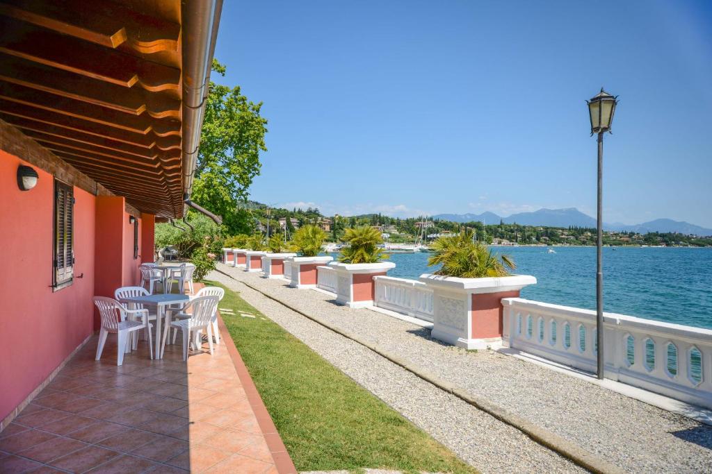 une terrasse avec une table et des chaises au bord de l'eau dans l'établissement VILLA GARUTI VILLAGE, à Padenghe sul Garda
