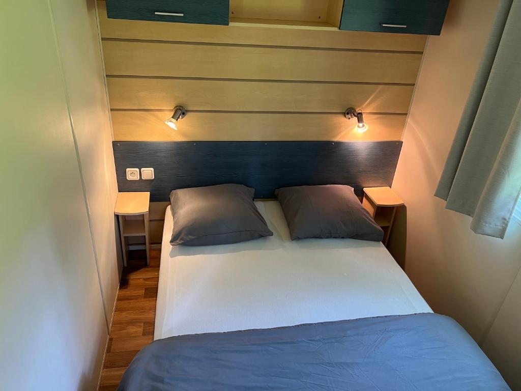 une chambre avec un grand lit avec deux oreillers dans l'établissement mobil home, à Saint-Chéron 32 autres photos