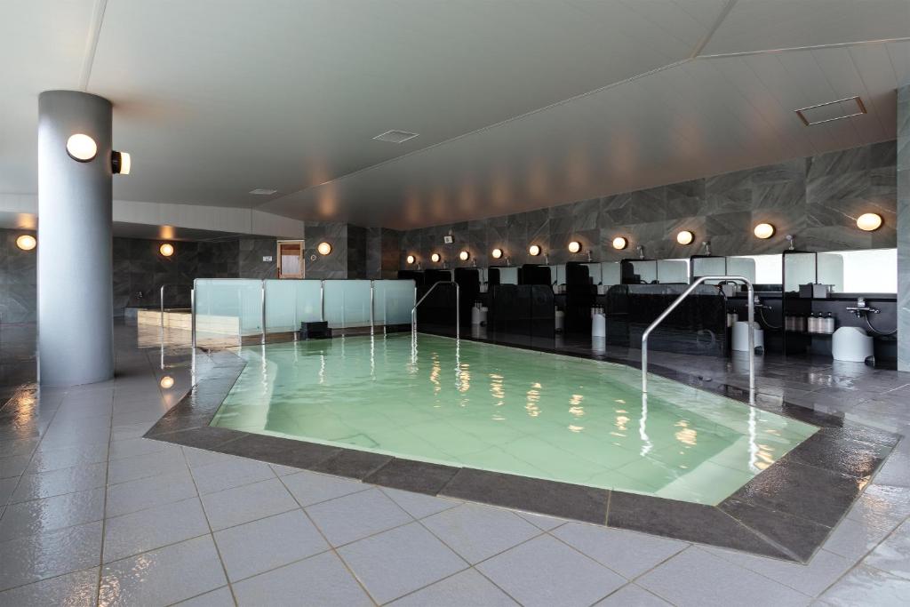 une grande piscine d'eau verte dans un bâtiment dans l'établissement Shogetsu Grand Hotel, à Jozankei