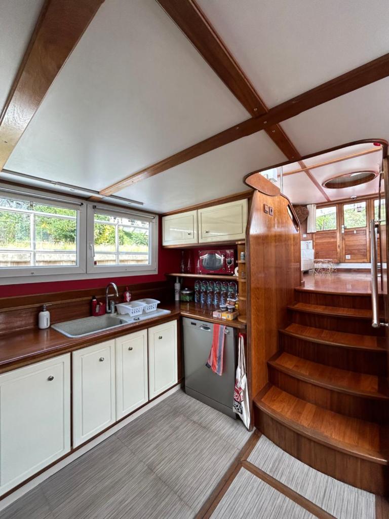 une cuisine avec un évier et un escalier dans une remorque dans l'établissement Péniche Design 115m2 Port Privé Vue Seine à 15min de Paris, à Asnières-sur-Seine 10 autres photos