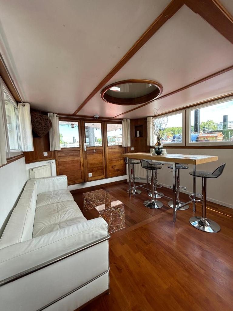 un salon avec un canapé et une table dans l'établissement Péniche Design 115m2 Port Privé Vue Seine à 15min de Paris, à Asnières-sur-Seine