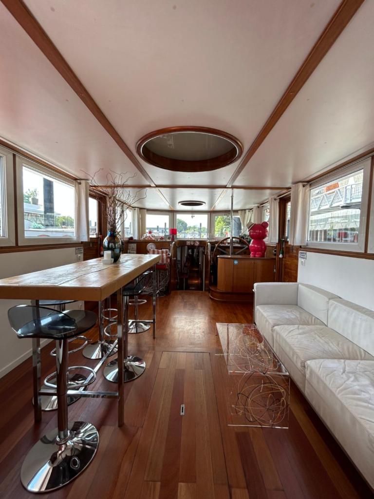 un salon avec un canapé et une table dans l'établissement Péniche Design 115m2 Port Privé Vue Seine à 15min de Paris, à Asnières-sur-Seine