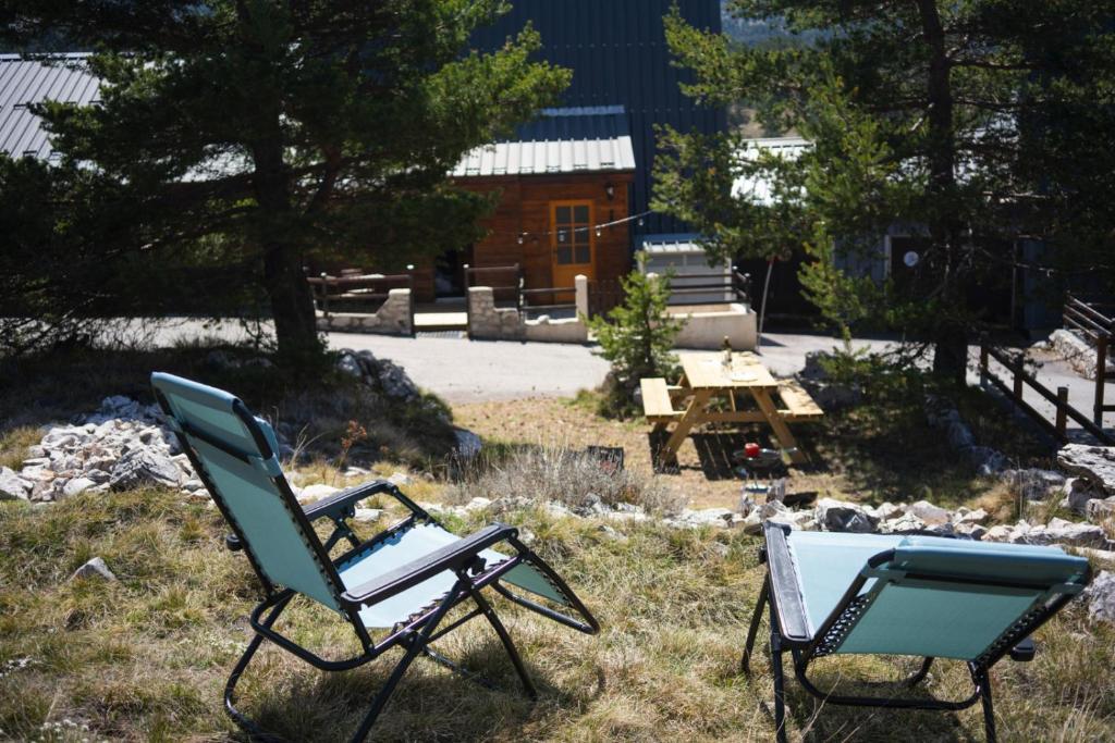 2 chaises longues assises dans l'herbe avec une table de pique-nique dans l'établissement Bel appartement type chalet avec balnéo et jardin, à Gréolières