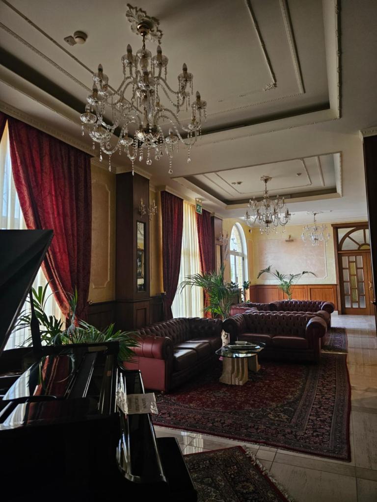 Elle comprend un salon doté d'un mobilier en cuir et d'un lustre. dans l'établissement Hotel Villa Santa Maria, à Villapiana